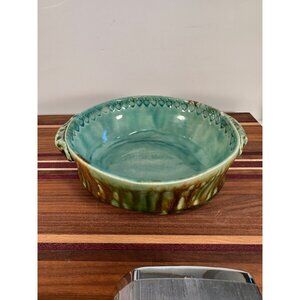 Round ceramic oven dish with turquoise inside with brown drip glaze on the exter